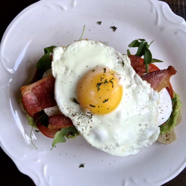 BLT Avocado Toast, a simple brunch recipe that combines avocado toast with a BLT and a sunny side up egg - via The Kittchen
