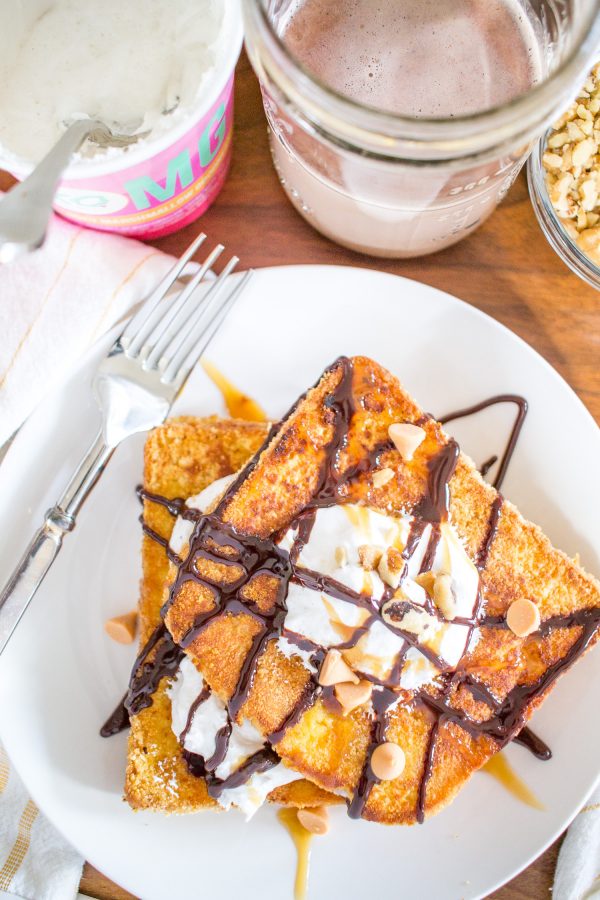 This decadent S’mores French Toast is the ideal special occasion breakfast. Soft brioche slices are dunked in a sweet vanilla milk and egg bath and then coated in graham cracker crumbs before being toasted in butter and then covered with fluff, chocolate sauce, caramel, butterscotch chips, and chopped walnuts.