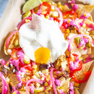 Brussels Sprout Nachos - cheesy nachos topped with roasted brussels sprouts, corn, pickled onions, fresno chilis, a fried egg, and a roasted garlic and beet crema.