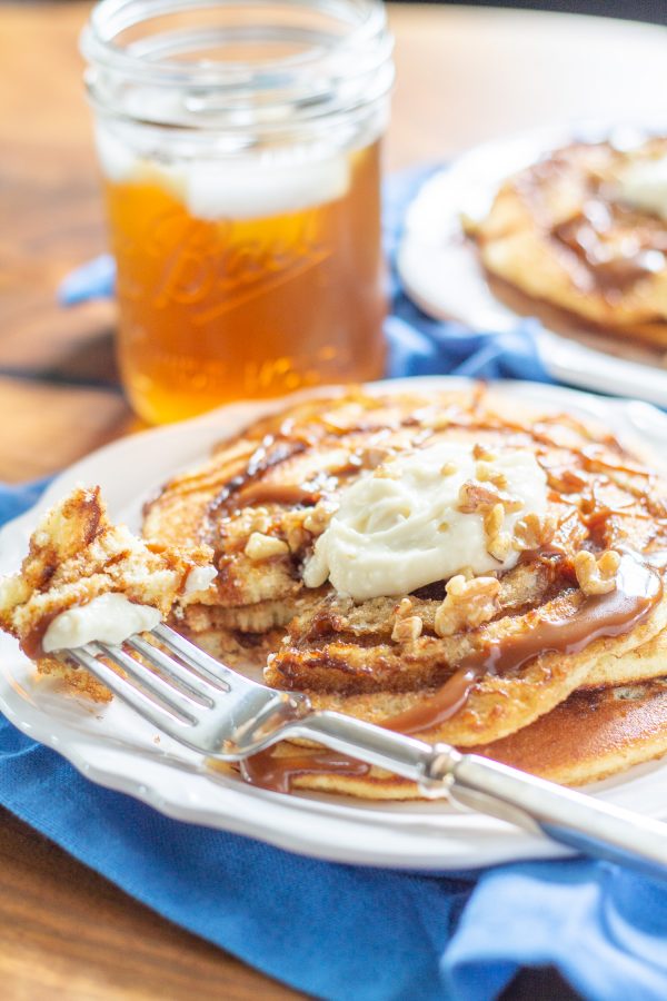 These decadent Cinnamon Roll Pancakes are made with vanilla cake batter swirled with cinnamon sugar, and topped with toffee sauce and cream cheese frosting. They are an over-the-top treat to serve for a birthday or special occasion.
