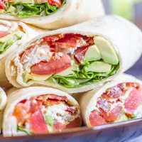 BLT Wraps | The classic BLT gets an upgrade with this easy recipe for BLT Wraps with Avocado and Mozzarella. This is the perfect low-fuss summertime meal. Crispy bacon gets paired with juicy tomatoes, fresh lettuce, slices of avocado, creamy fresh mozzarella cheese, and a touch of mayonnaise. It is a medley of well-loved ingredients, and a perfect way to serve ripe end-of-summer tomatoes. When my friend was hosting a picnic in Lincoln Park, I wanted to bring one of my favorite summertime foods, the BLT. Instead of just adding bacon, lettuce, and tomato, I also added in some shredded fresh mozzarella, and some slices of avocado. And since BLTs have a tendency to fall apart, I made BLT wraps so that I could add more ingredients without worrying about the sandwiches falling apart. I love this recipe because it is easy to make enough to serve a crowd. The only cooking involved in this recipe is cooking the bacon, which can easily be done in large batches. Once the bacon is ready, you can assemble enough wraps to feed the whole family in just 10 minutes. The easiest way to prepare the bacon is to bake it on a sheet pan. While the bacon is cooking, chop the tomatoes, wash the lettuce, grate the mozzarella, and slice the avocado. Once the bacon has cooked, let it cool and then assemble the BLT Wraps. I like to let the bacon cool so that way it doesn't melt the mozzarella. I recommend making these BLT Wraps just before serving, otherwise, the juicy tomato might make the wrap and bacon soggy. And, use the largest tortillas that you can find. I like to buy the Burrito Grande size since they are just the right size to hold lots of ingredients. I am not going to get into specific proportions in the recipe, you can make these BLT Wraps however you like - I recommend preparing 2-3 slices of bacon per wrap. How to make BLT Wraps with Avocado and Mozzarella: Bacon Tomatoes Avocado Lettuce Fresh Mozzarella Mayonnaise Large Tortillas Begin by preparing the bacon. Line a baking sheet with aluminum foil, and lay the bacon out in a single layer. Bake at 375 degrees for about 15 minutes, until the bacon is crispy. Place the cooked bacon on paper towels and blot the excess grease. While the bacon is cooking, chop the tomatoes, slice the avocado, wash the lettuce, and grate or slice the mozzarella. To assemble the wraps, spread some mayonnaise in the center of a tortilla. I use about a teaspoon per tortilla. Then add 2-3 slices of bacon, some chopped tomatoes, sliced avocado, mozzarella, and lettuce. Fold the sides of the tortilla over, and then roll the wrap up. Continue making as many wraps as you like. Slice them in half and serve.