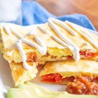 Breakfast Quesadillas have become our favorite weekend breakfast. This meal combines cheesy scrambled eggs with crispy bacon and fresh tomatoes inside crispy tortillas. Serve the quesadillas sliced into triangles with salsa, guacamole, and/or sour cream for dipping.