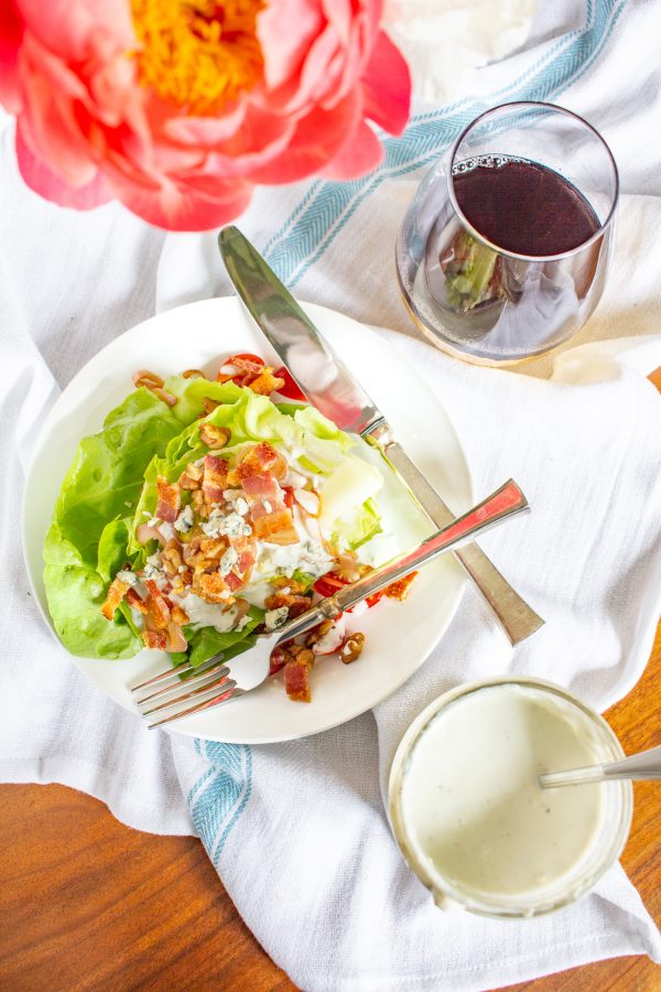 The Best Wedge Salad | A wedge salad is topped with maple toasted walnuts, thick cut bacon, grape tomatoes, caramelized shallots, and homemade chunky blue cheese dressing. 