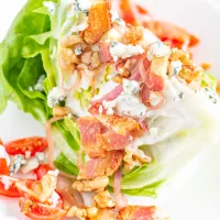 The Best Wedge Salad | A wedge salad is topped with maple toasted walnuts, thick cut bacon, grape tomatoes, caramelized shallots, and homemade chunky blue cheese dressing.