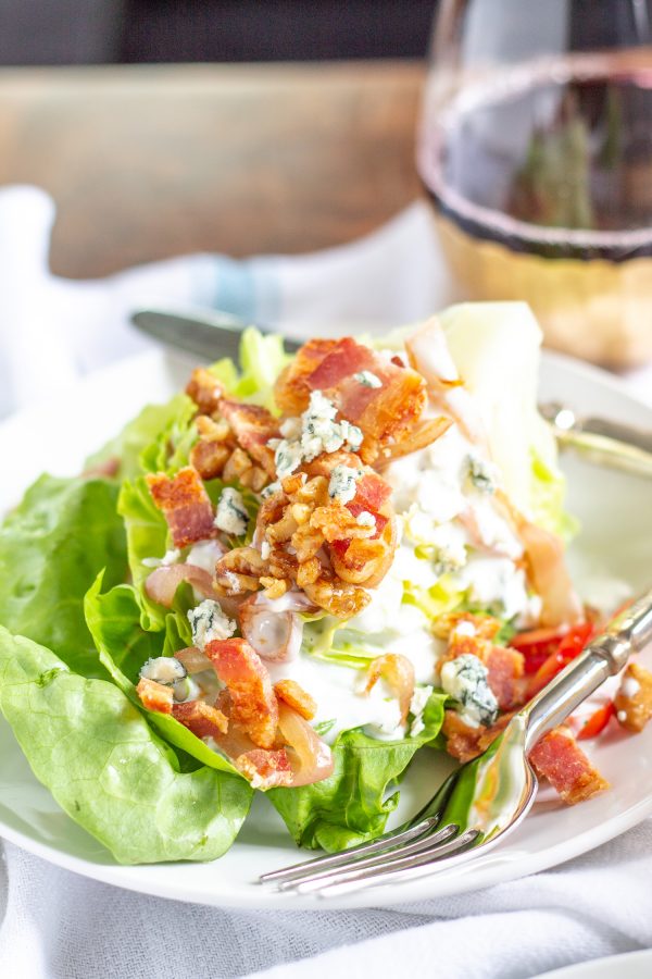 The Best Wedge Salad | A wedge salad is topped with maple toasted walnuts, thick cut bacon, grape tomatoes, caramelized shallots, and homemade chunky blue cheese dressing.