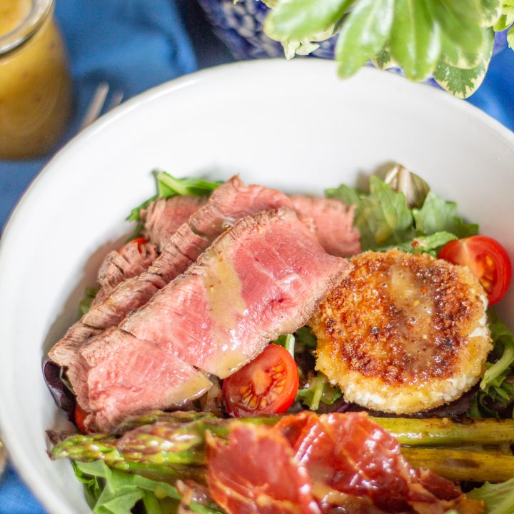 Steak and Fried Goat Cheese Salad a complete meal with greens, asparagus, tomatoes, crispy prosciutto, fried goat cheese, steak, and a light roasted garlic and mustard dressing.