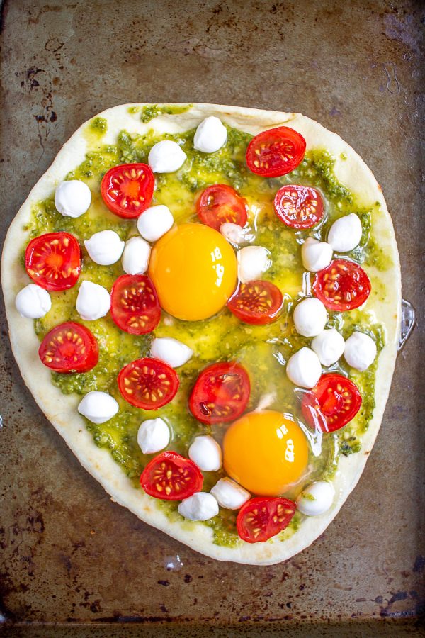 Breakfast pizza is a delicious homemade breakfast that can be made in under 20 minutes. Frozen naan gets topped with pesto, tomato, cheese, and eggs for a simple meal.