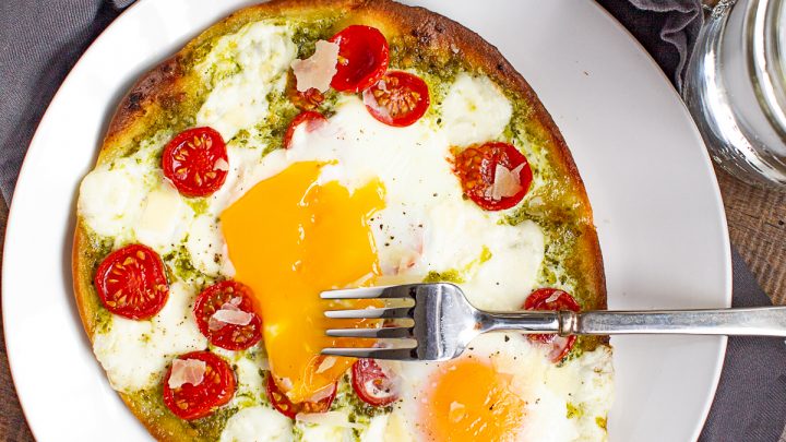 Breakfast pizza is a delicious homemade breakfast that can be made in under 20 minutes. Frozen naan gets topped with pesto, tomato, cheese, and eggs for a simple meal.