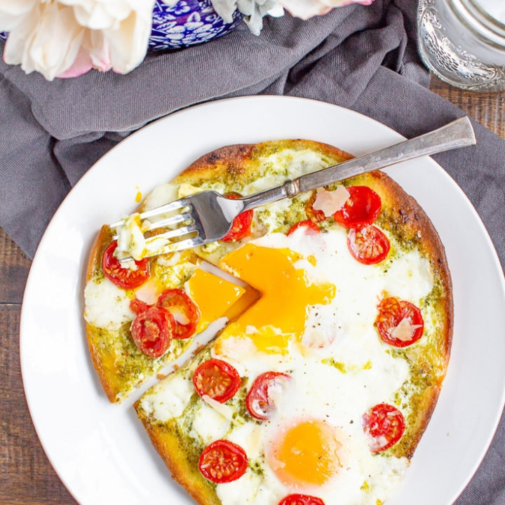 Breakfast Pizza | Breakfast pizza is a delicious homemade breakfast that can be made in under 20 minutes. Frozen naan gets topped with pesto, tomato, cheese, and eggs for a simple meal.