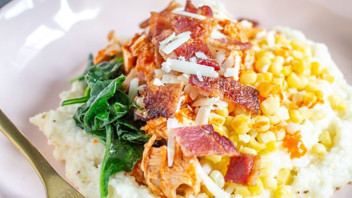 A Buffalo Chicken Grits Bowl is made with creamy cheesy grits, crispy bacon, sauteed spinach, fresh corn, and spicy shredded buffalo chicken. It's a comfort food meal that you can make in just 30 minutes.