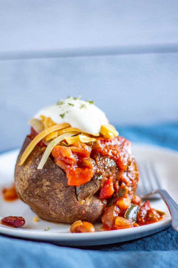 Chili Potatoes are baked potatoes filled with chili and topped with sour cream and cheddar cheese. It's a simple way to serve leftover chili that makes it feel like a whole new meal.