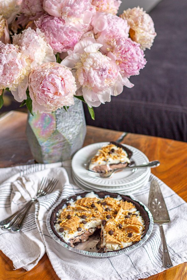This easy Ice Cream Pie recipe is made with two layers of ice cream with chocolate fudge sauce and it’s topped with nuts, waffle cone chunks, and chocolate chips. It’s similar to an ice cream sundae but it can be prepared in advance and it’s easier to serve!